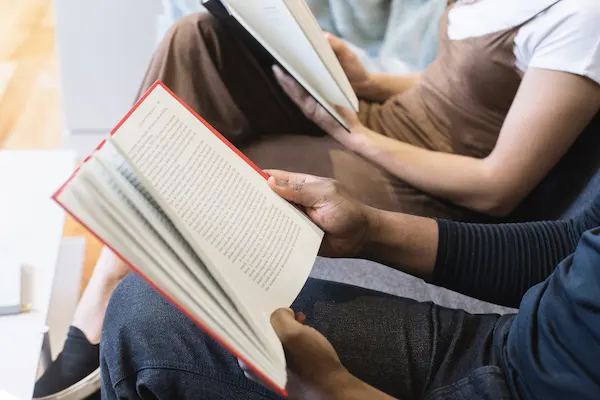 people sitting on a bench reading books